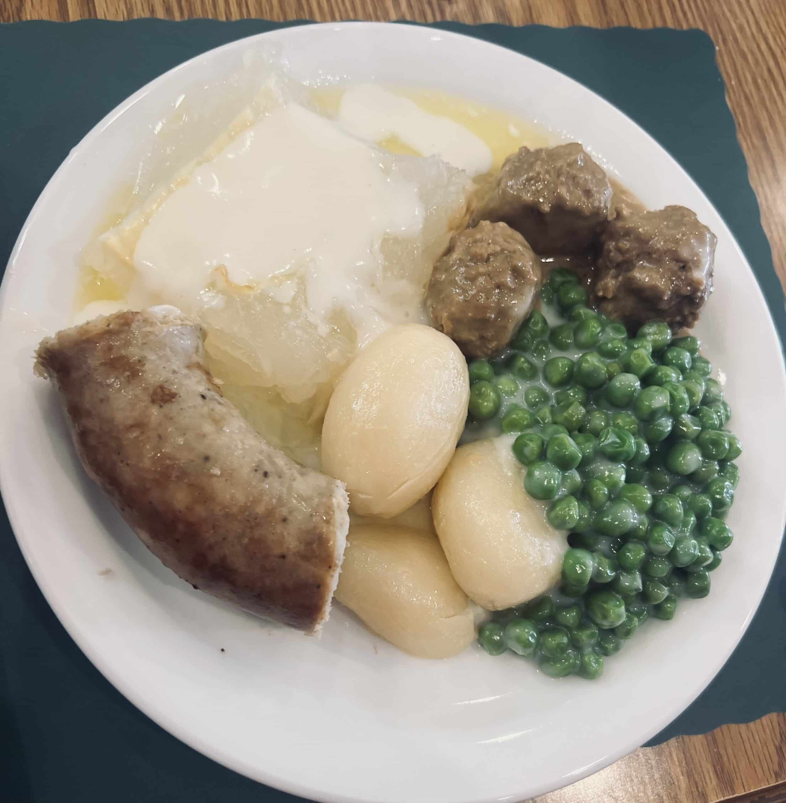 dinner plate with peas, sausages and potatoes