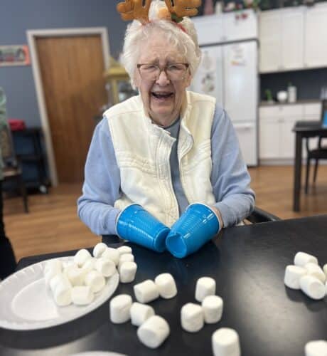 elder with blue cups on her hand and marshmallows on the table
