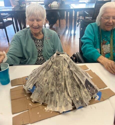 two senior building a volcano with cardboard and newspaper